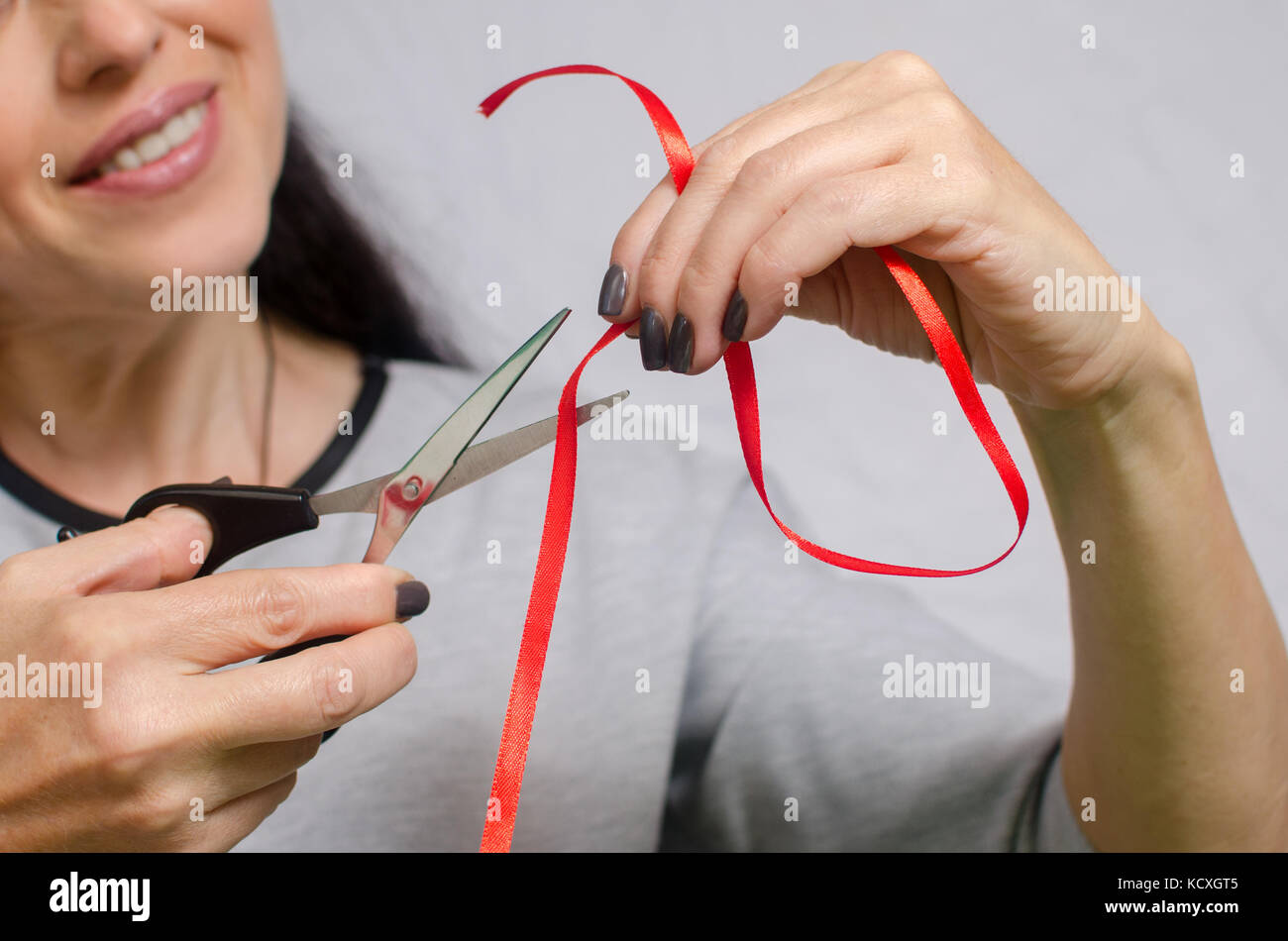 woman cuts a red ribbon with scissors to make a decoration Stock Photo