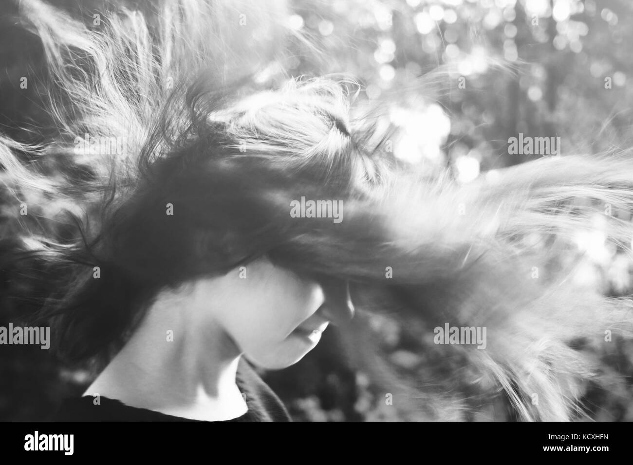 Young girl with long hair standing on strong wind. black and white Stock Photo