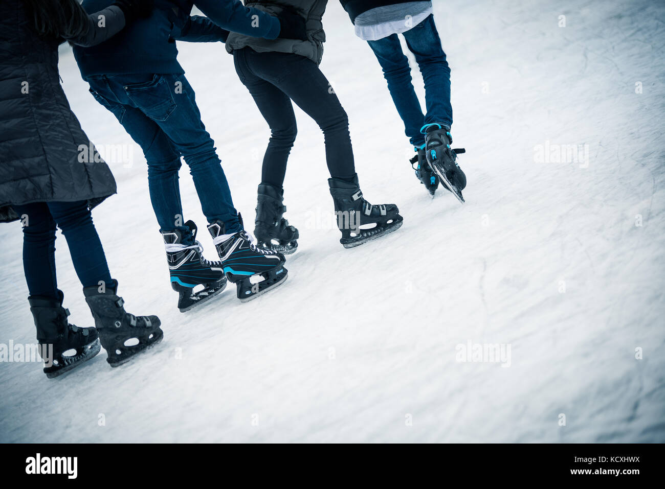 Four young people skating on ice Stock Photo