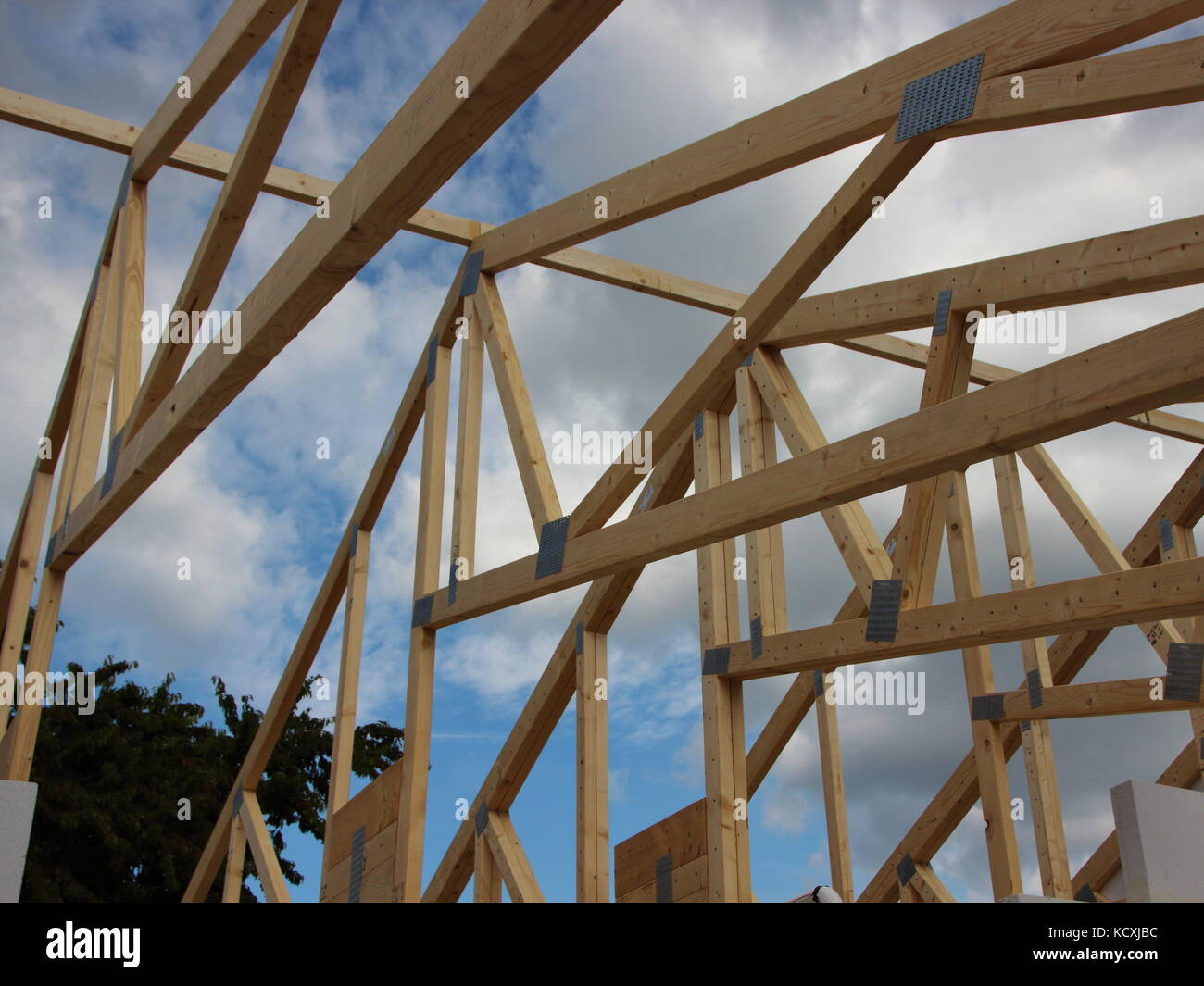Roof Rafter Construction on Building Site with Sky and Clouds Stock Photo