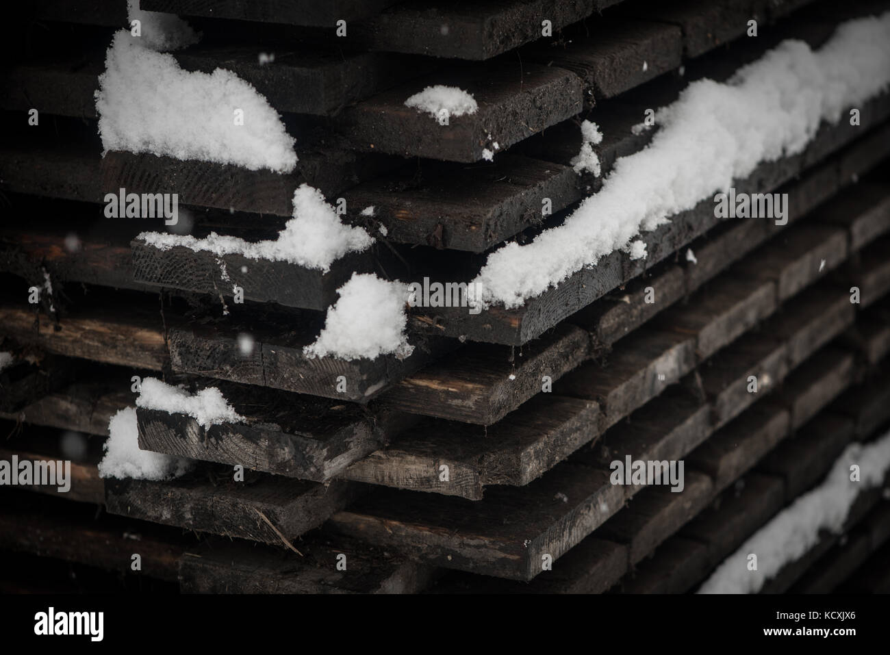 Stacks of construction wood in winter covered with snow Stock Photo