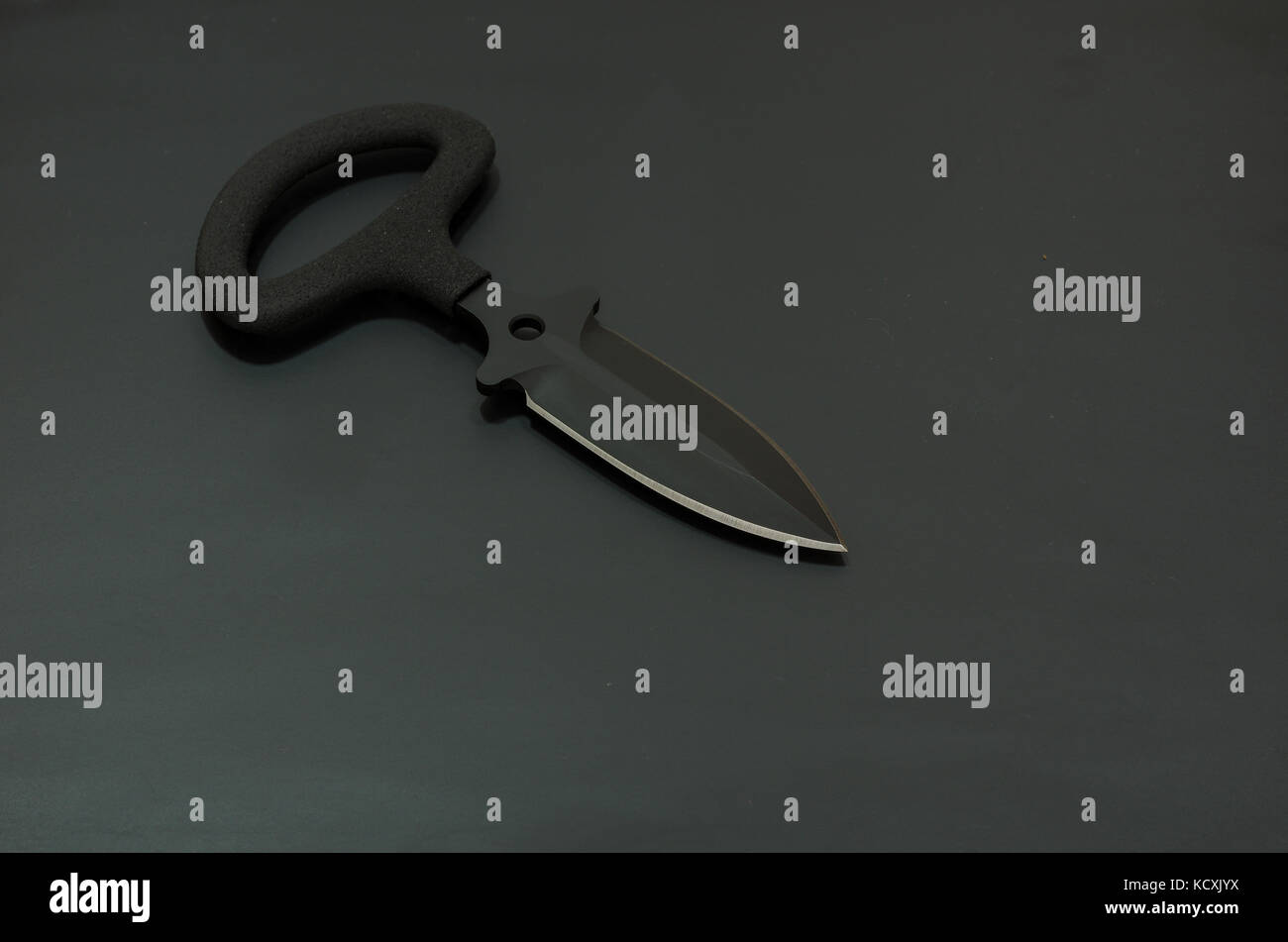 Black knife on a black background. A lot of air in the frame. Military composition. Stock Photo