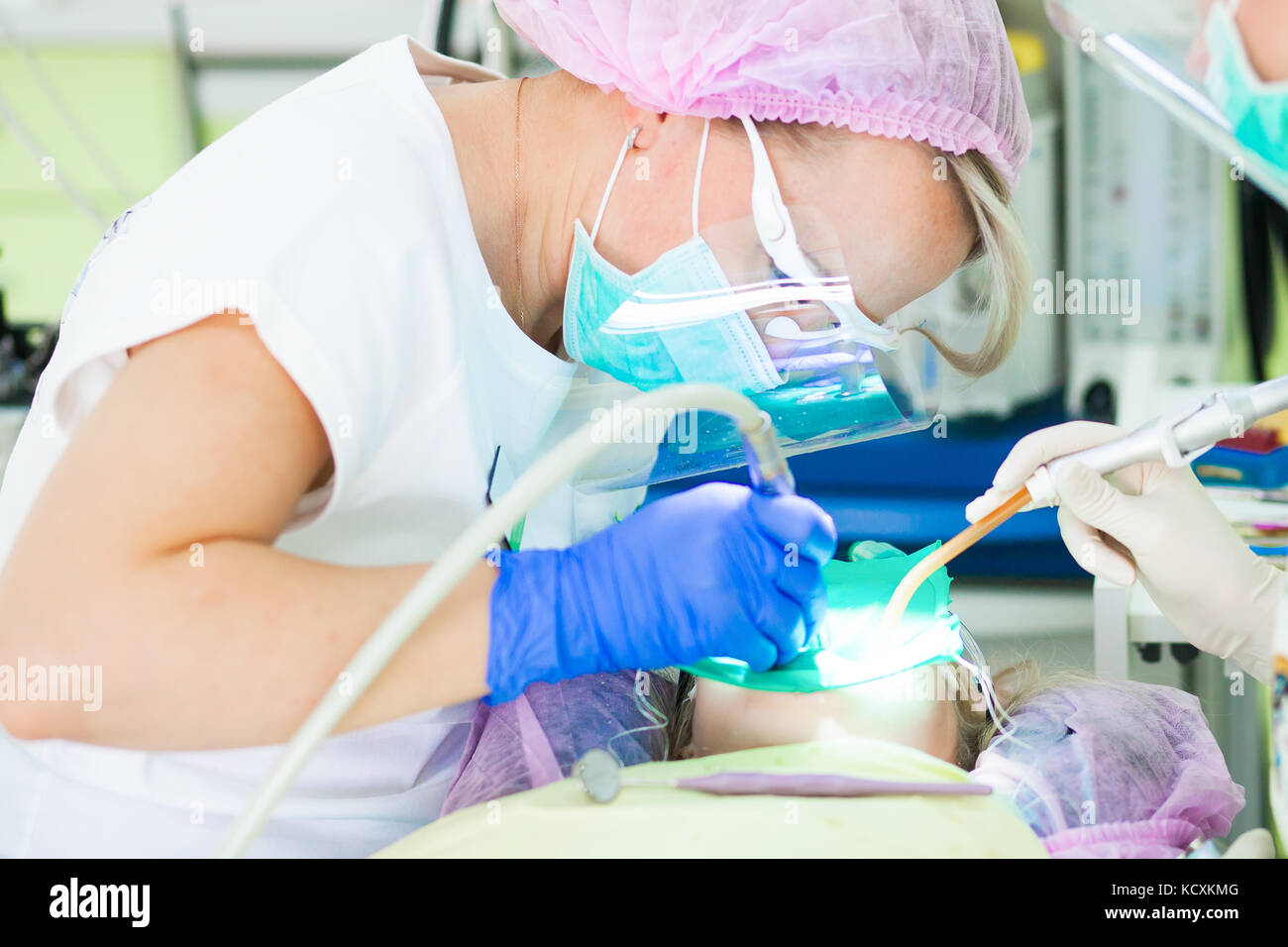 Young female dentist in a pink sterile hat, a medical white uniform ...