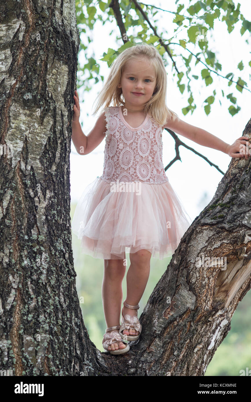 Little Girl With Blue Eyes On The Tree In Summer Wearing Beautiful