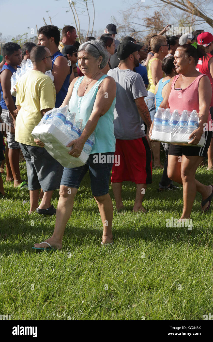 Puerto Rican locals carry cases of water delivered by the U.S. Army