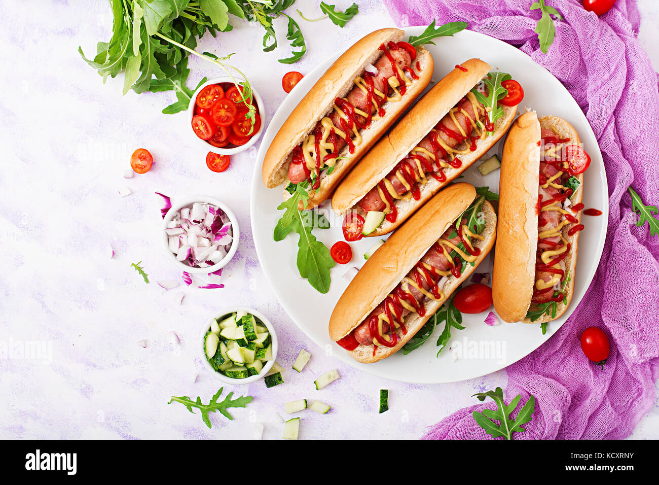 Hot dog with sausage. bacon, cucumber, tomato and red onion on white