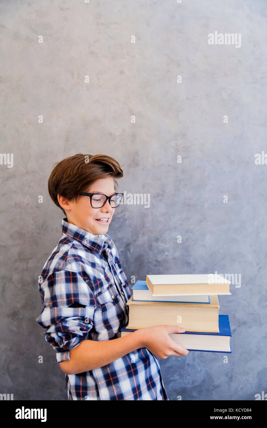 Cute teenage school boy holding books against wall Stock Photo - Alamy