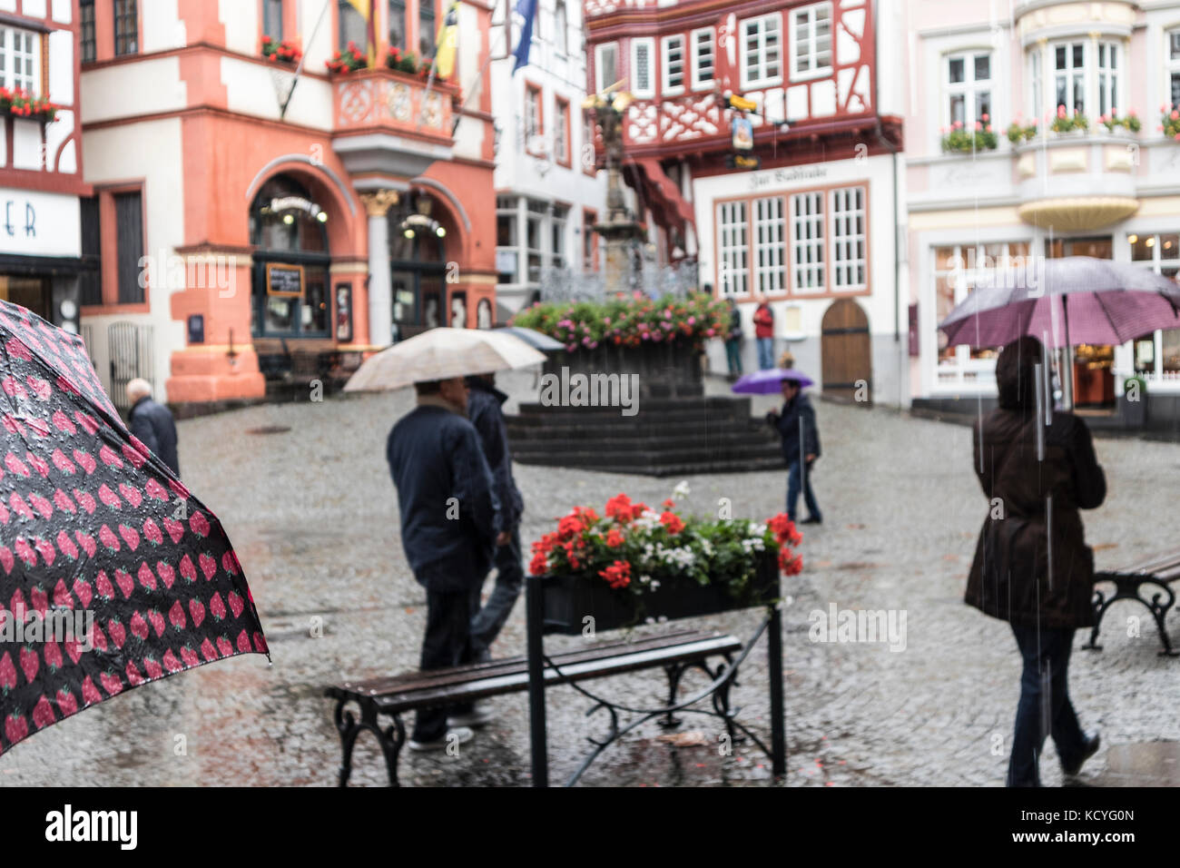 A wet, rainy day at the town of Bernkastel-Kues, in the Mosel Valley, Germany. The tourists have umbrellas. The main focus point is the pink umbrella Stock Photo
