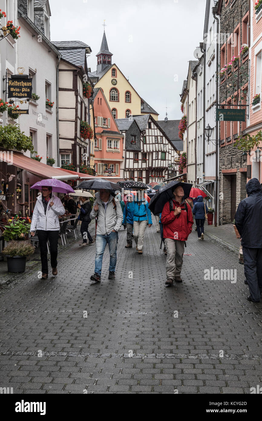 A wet, rainy day at the town of Bernkastel-Kues, in the Mosel Valley, Germany. The tourists have umbrellas to protect from the rain. Stock Photo