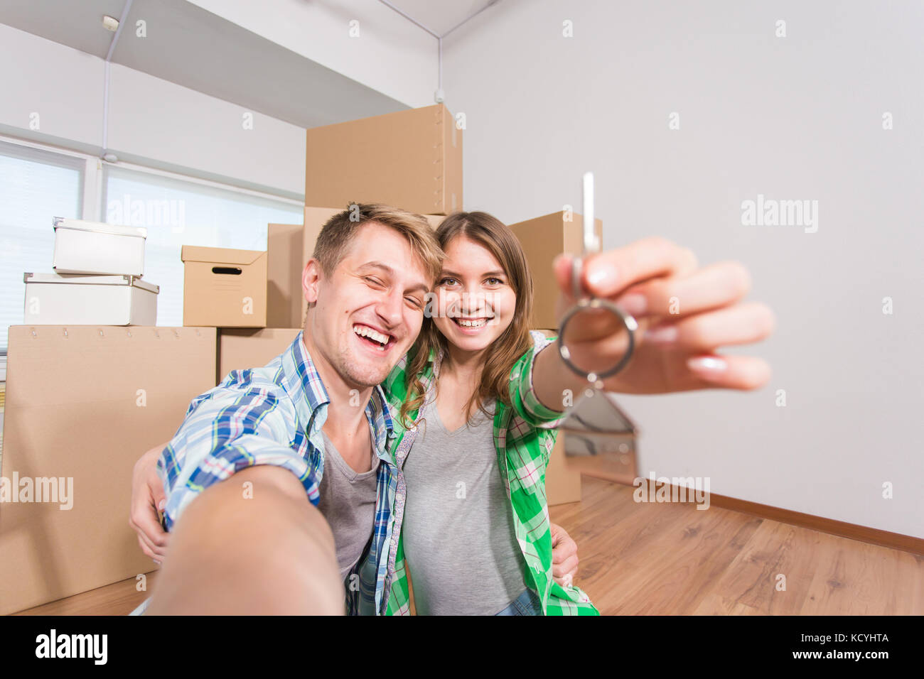 Happy funny couple embracing and showing house key in their new home ...