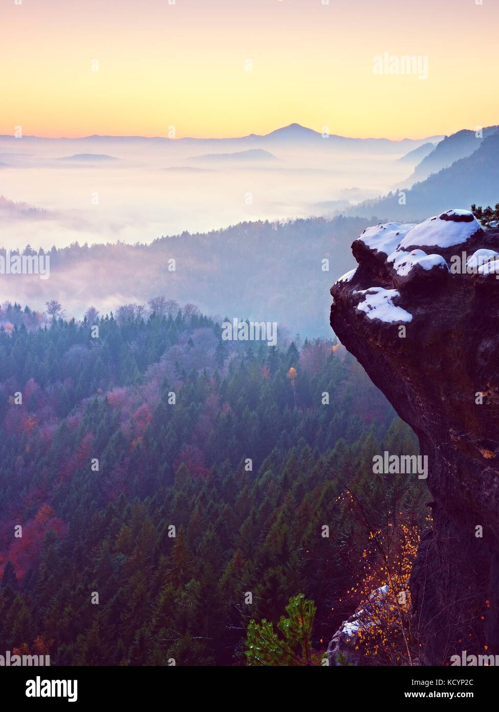 Pink daybreak in hilly landscape. Early winter misty morning in beautiful rocky hills. Peaks of hills in heavy fog. Miracle of nature Stock Photo