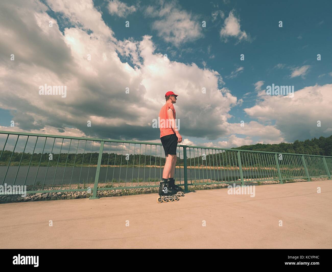 Rear view to inline skater in red tshirt and black pants skating on