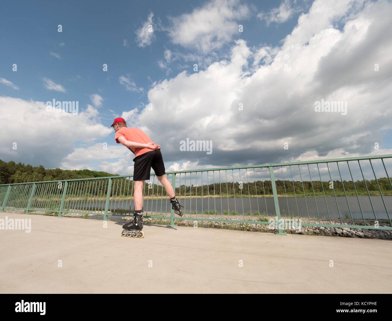 Roller skater in action. Man ride in inline skates ride along promenade handrail, blue sky in