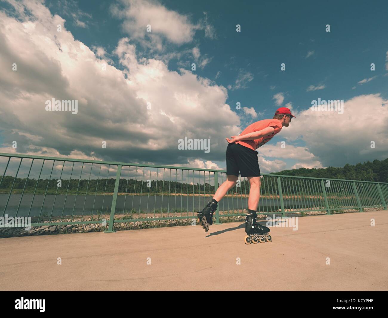 Rear view to inline skater in red tshirt and black pants skating on