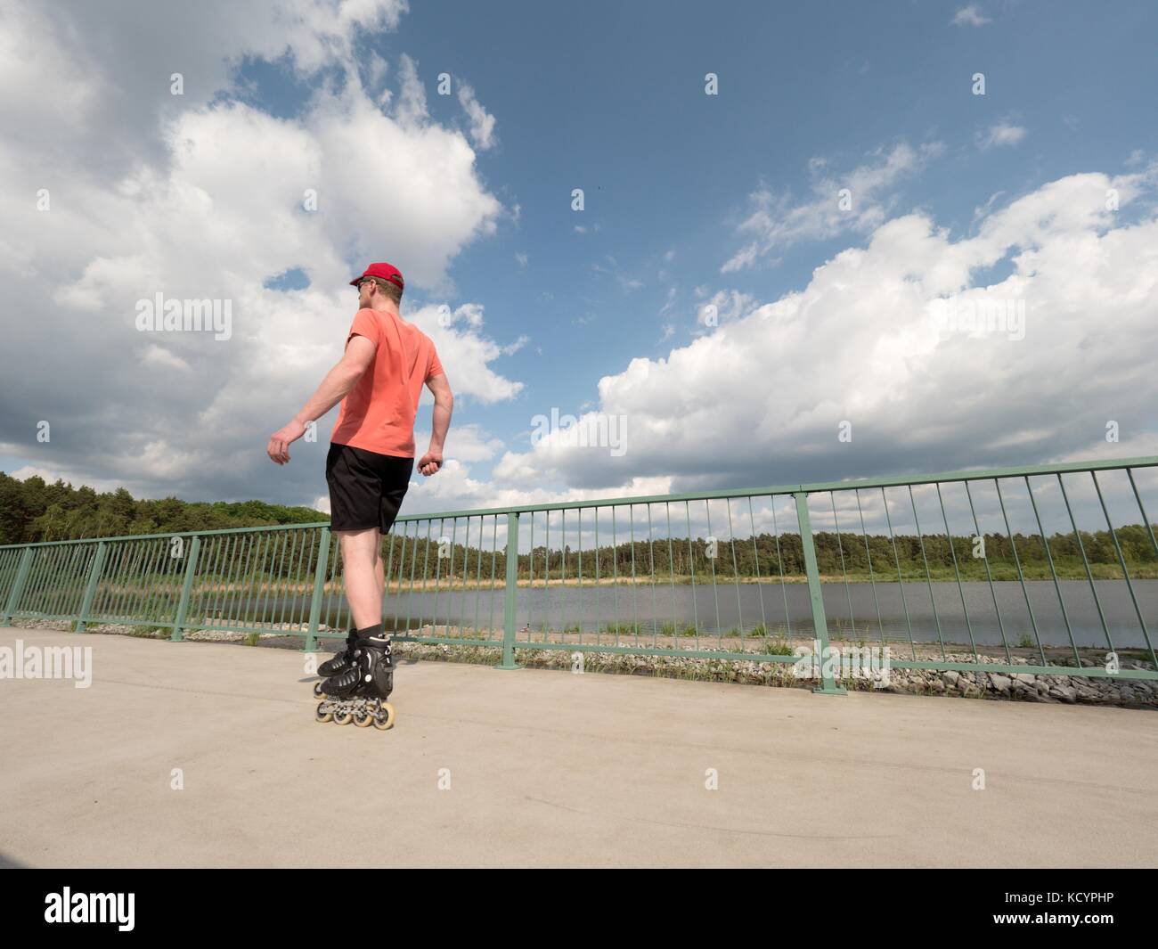 Roller skater in action. Man ride in inline skates ride along promenade handrail, blue sky in