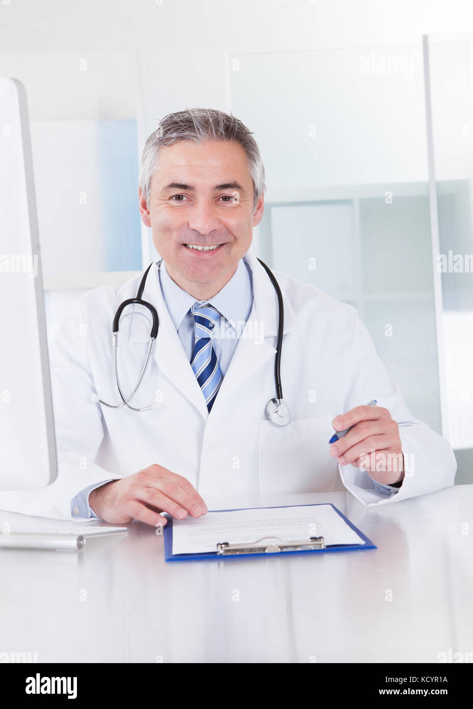 Portrait Of Happy Mature Male Doctor Working At Desk Stock Photo - Alamy