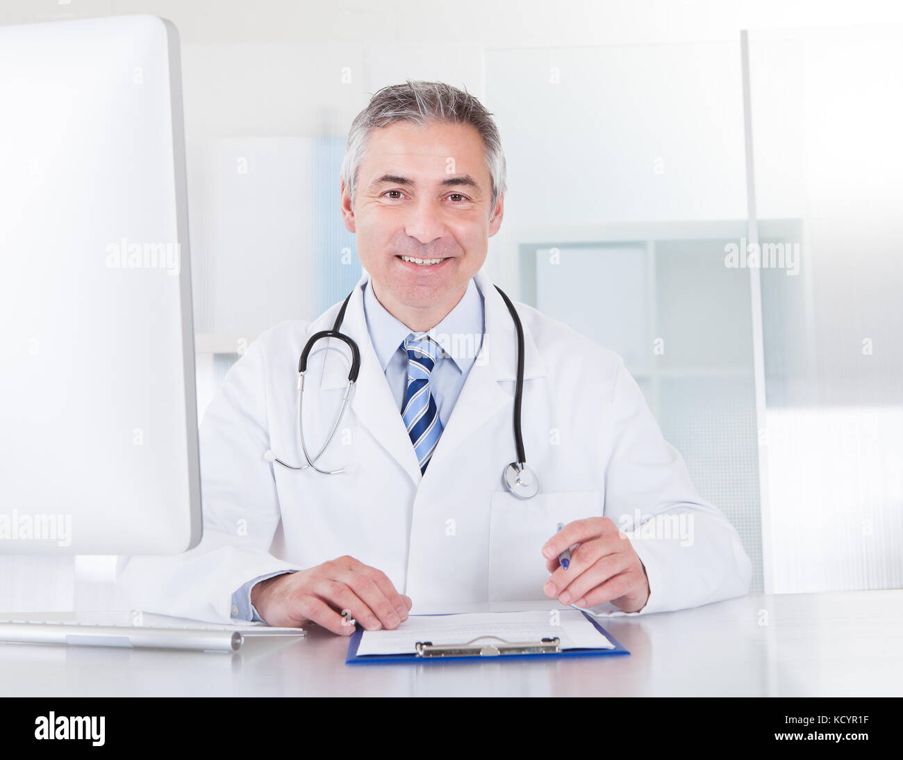 Portrait Of Happy Mature Male Doctor Working At Desk Stock Photo - Alamy