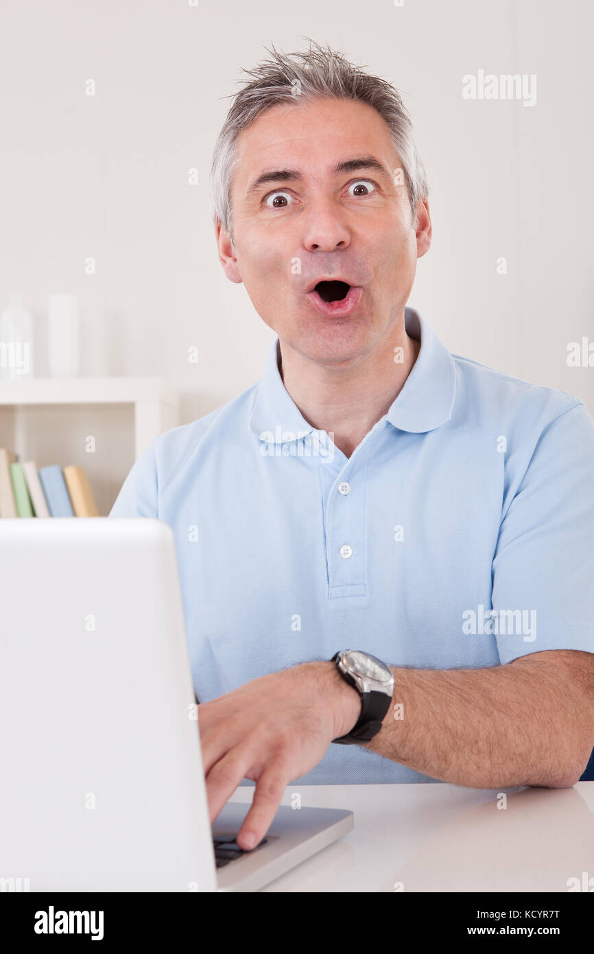 Portrait Of Excited Businessman Working On Laptop Stock Photo