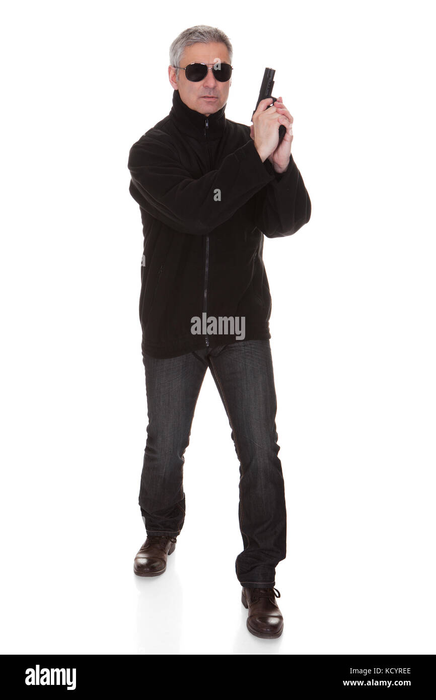 Mature man holding gun over white background Stock Photo