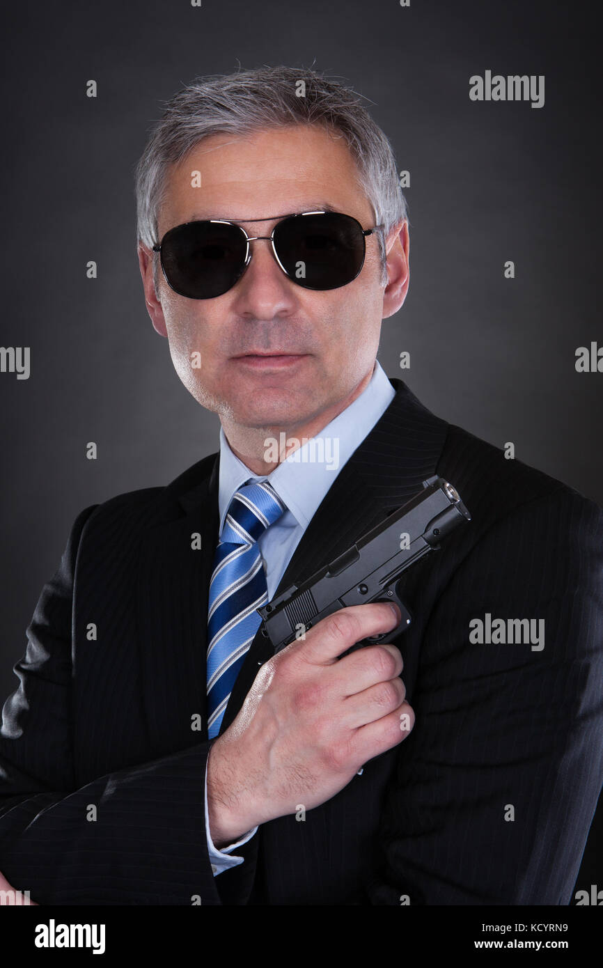 Portrait Of Male Detective With Handgun Over Black Background Stock Photo