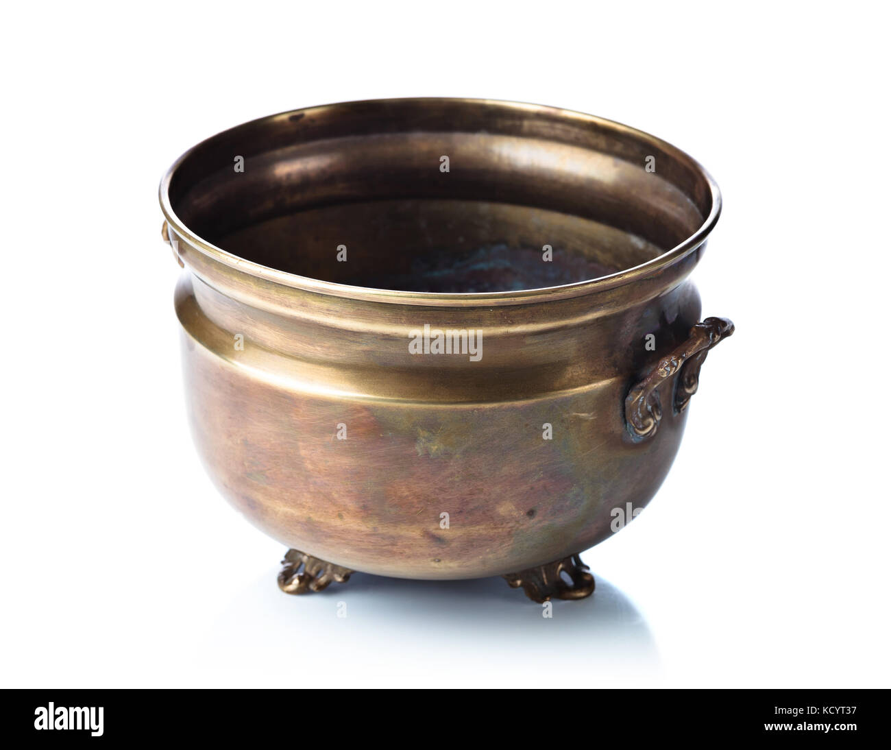 Empty old brass pot with decorative handles and legs isolated on a
