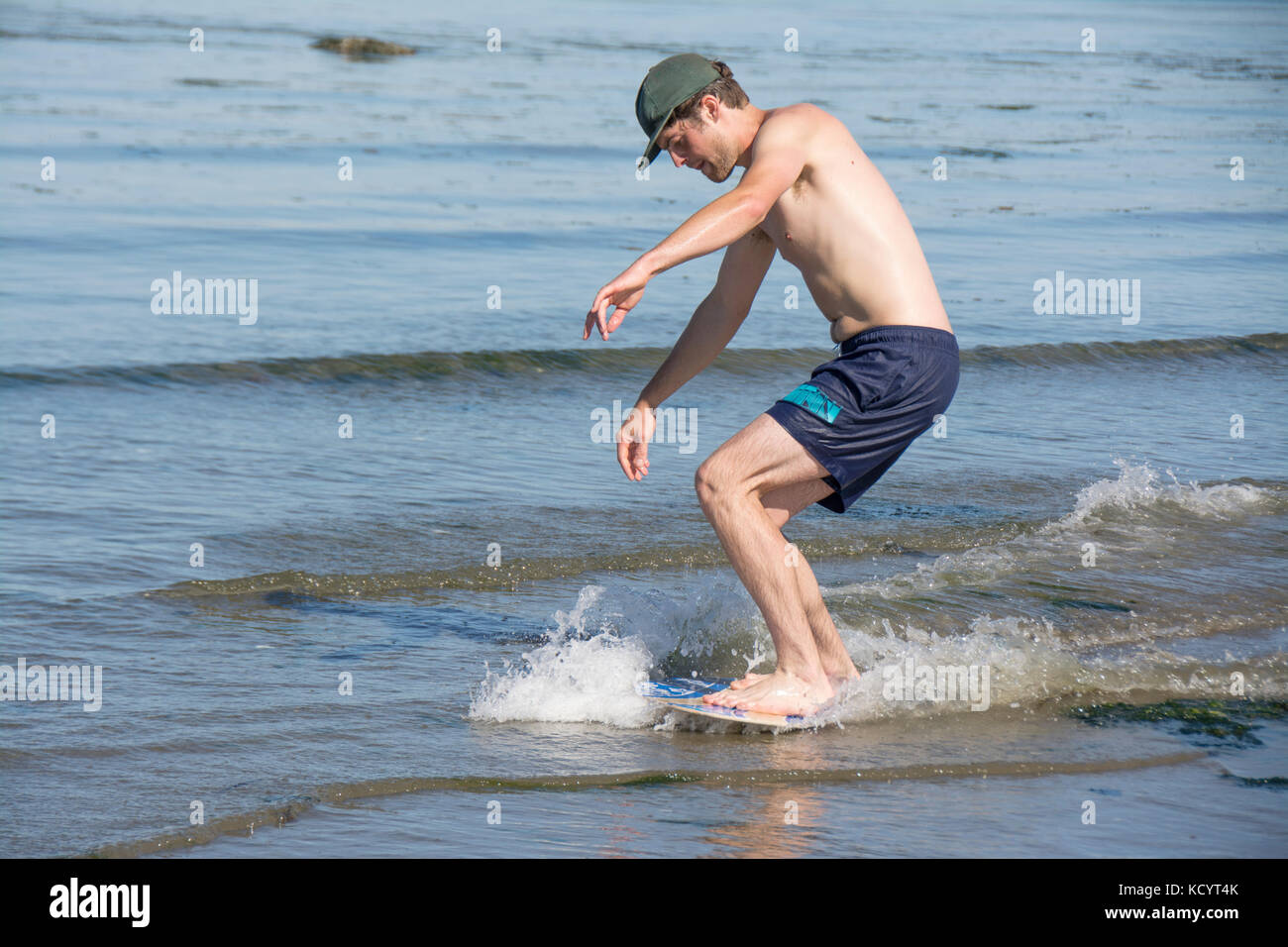Young man skim boarding on the beach at Sidney Island, British Columbia, Canada Stock Photo