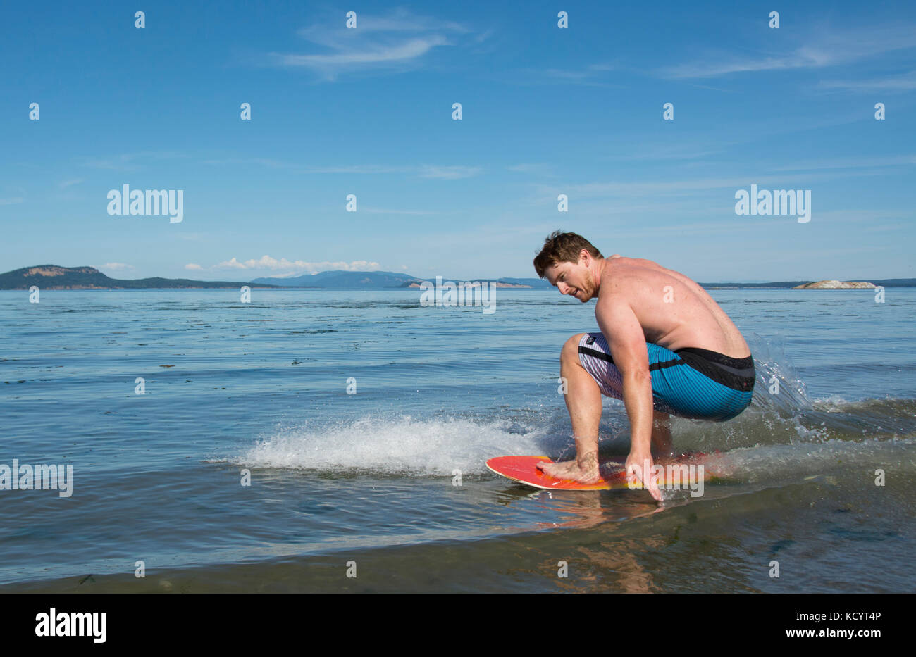 Young man skim boarding on the beach at Sidney Island, British Columbia, Canada Stock Photo