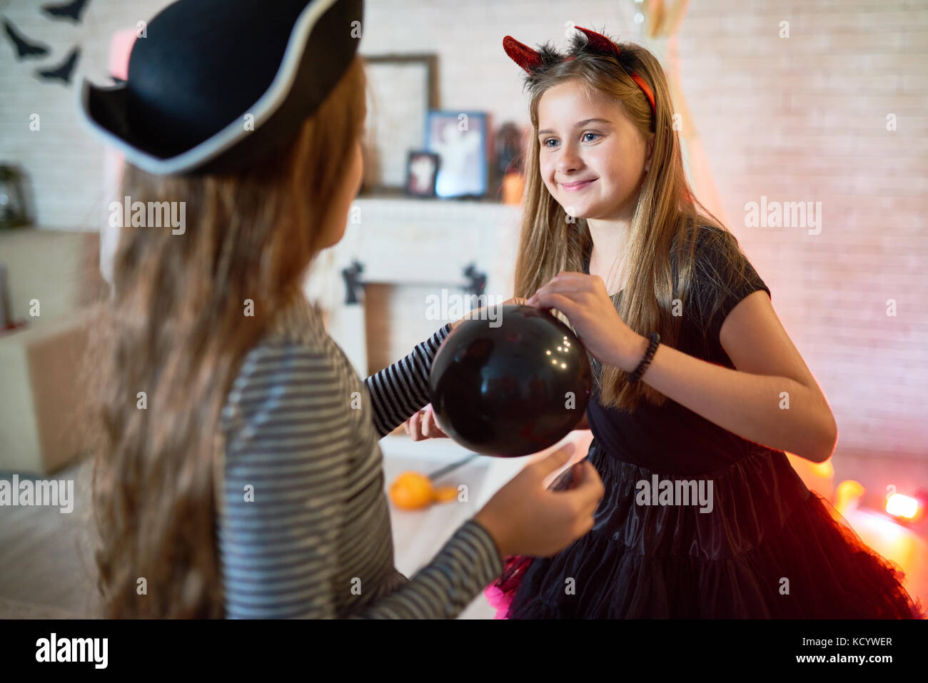 Portrait of two pretty gills wearing costumes decorating room for