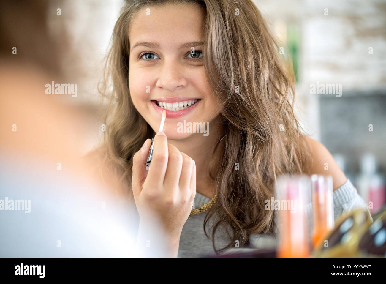 Young woman putting lip gloss on hires stock photography and images
