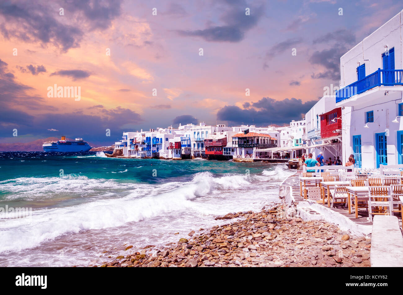 Little Venice, Mykonos island, Greece. Colorful buildings and balconies near the sea and a large white cruise ship. Stock Photo