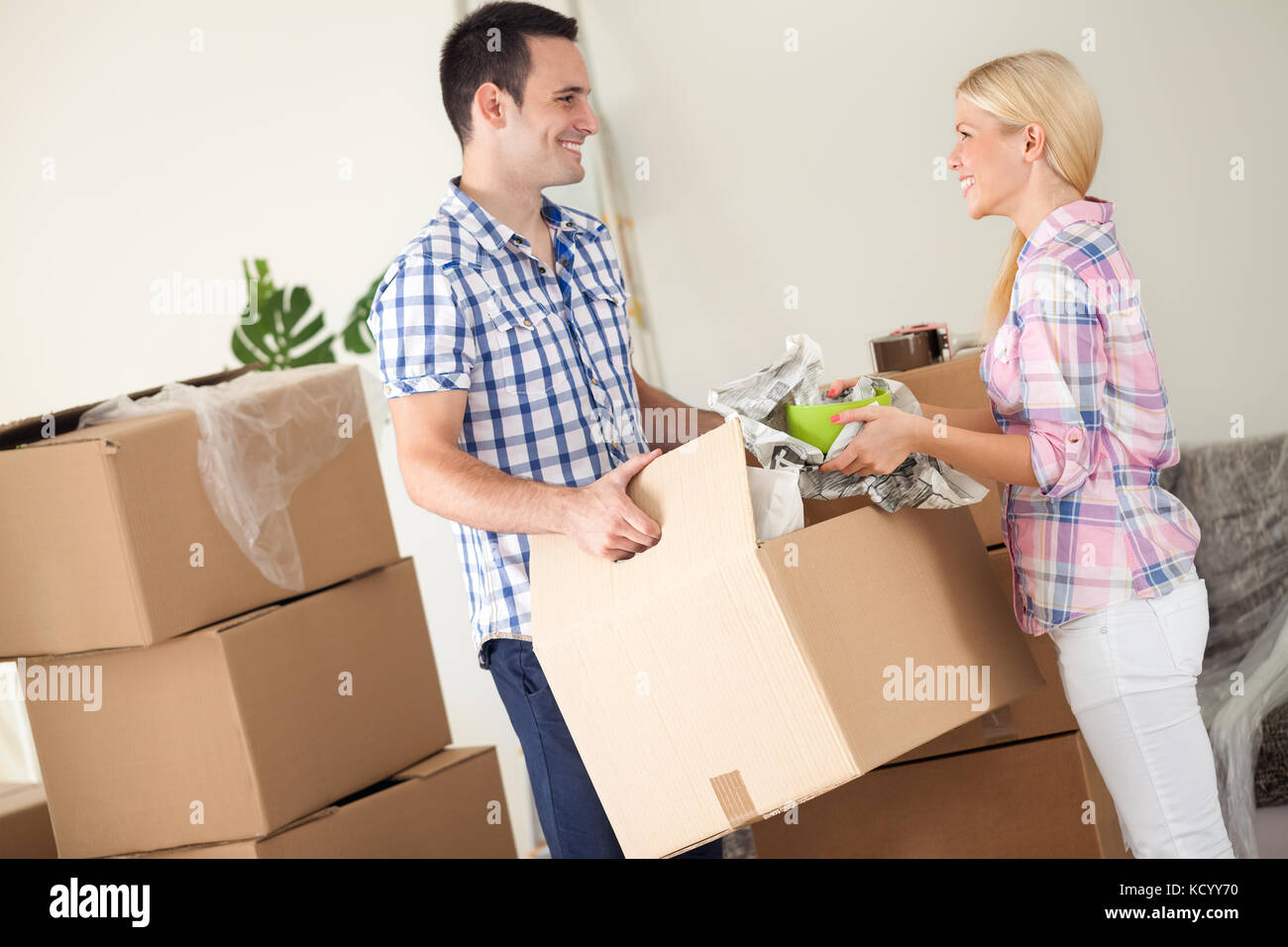 Couple with box moving into new home, smiling Stock Photo - Alamy