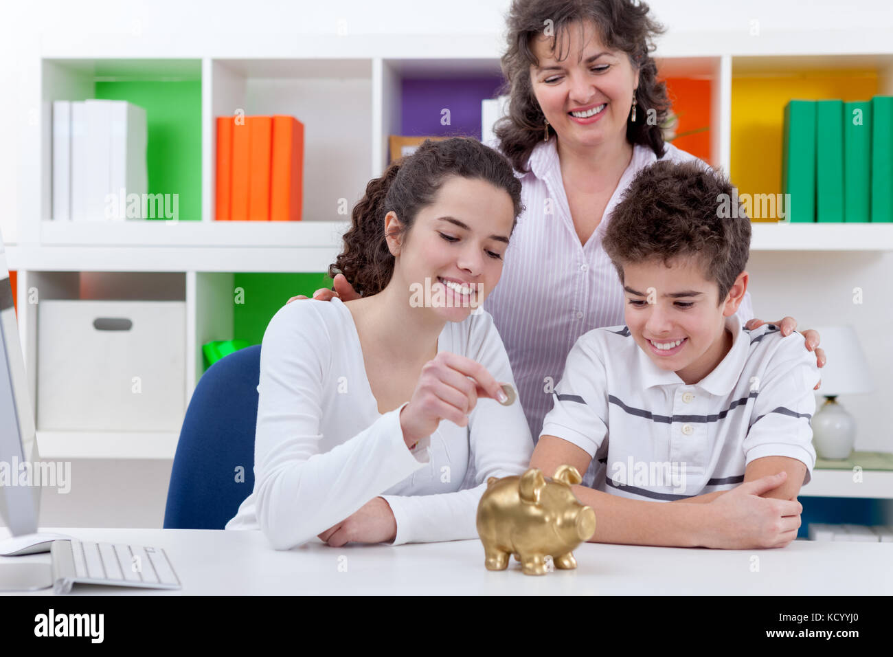 mother with her children putting money in piggybank, family saving ...
