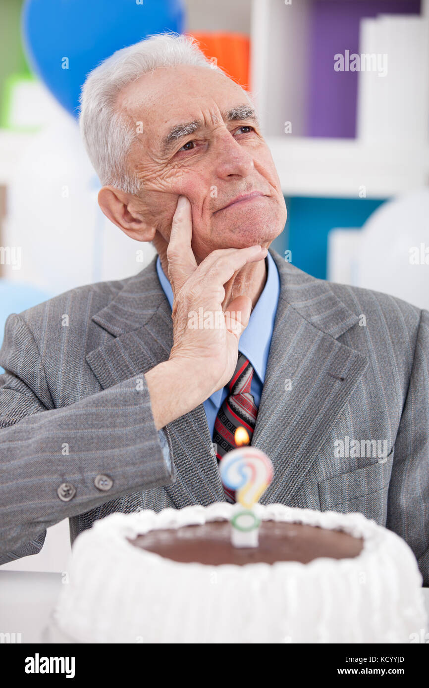 senior man with birthday cake thinking how old is Stock Photo Alamy