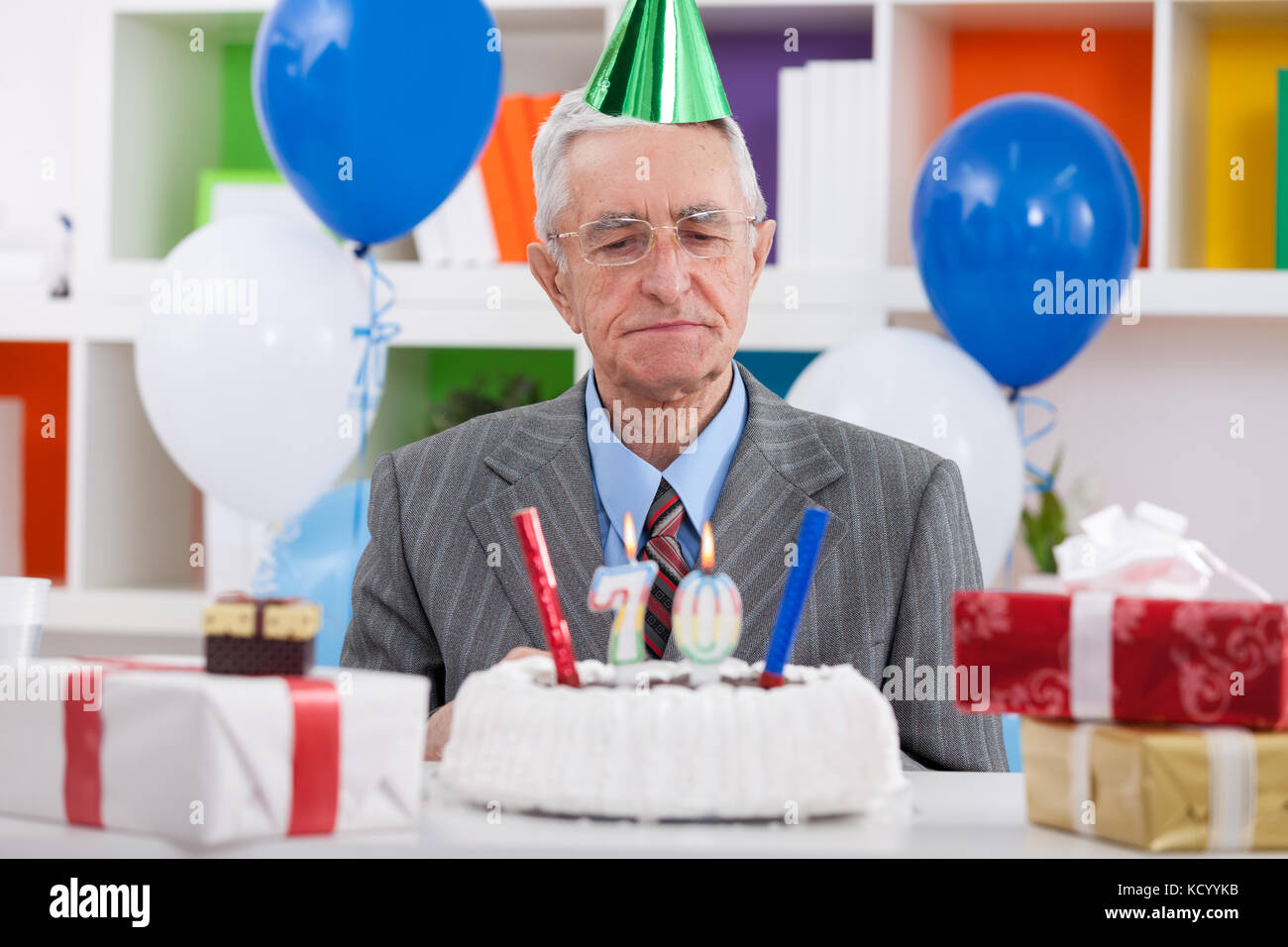 Senior man looking at his birthday cake for 70th birthday Stock Photo