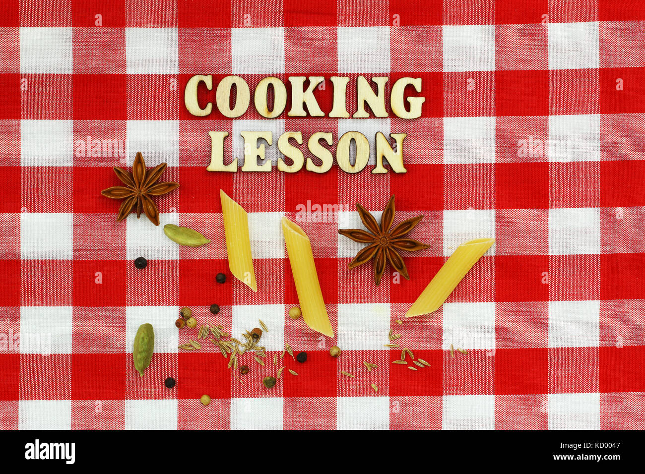 Cooking lesson written with wooden letters, pasta and spices on red and white checkered cloth Stock Photo