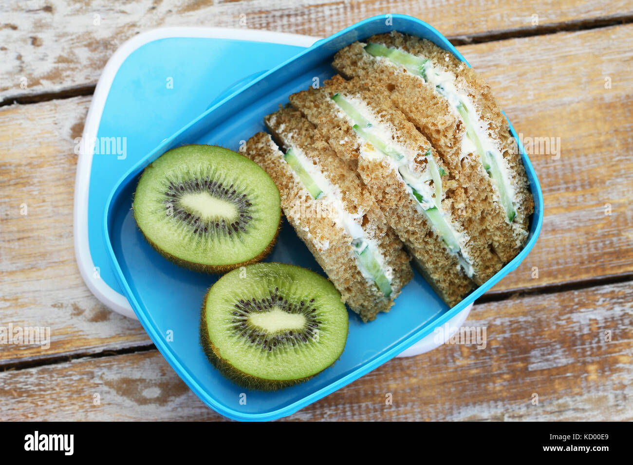 Brown bread sandwiches with cream cheese and cucumber and kiwi fruit in