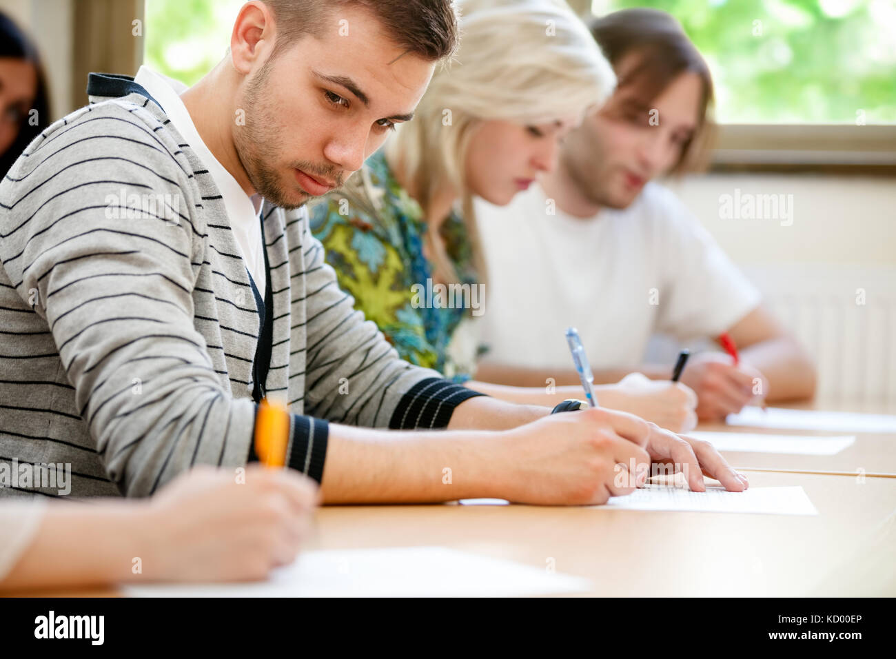 college student trying to copy off a student's test paper. Stock Photo