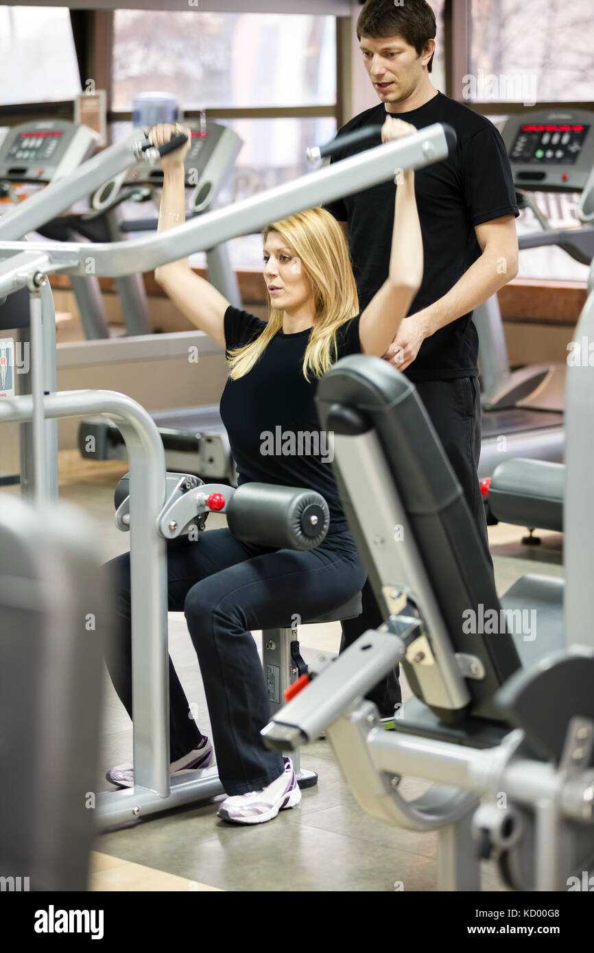 Woman exercise with her personal fitness trainer in the gym, Weight ...