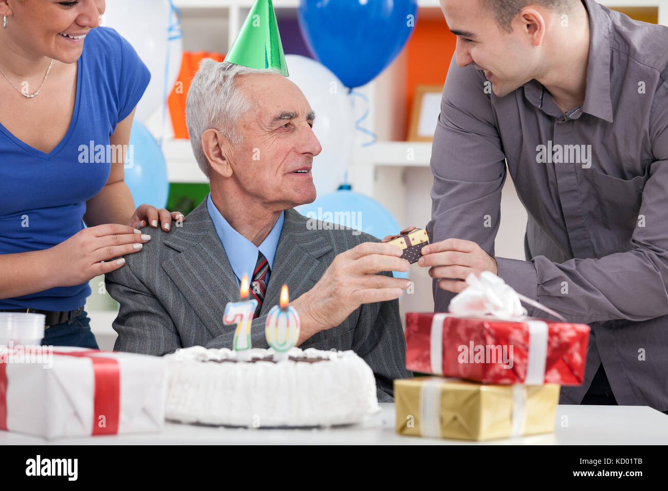 Senior man celebrating his birthday with family and cake with  candles Stock Photo