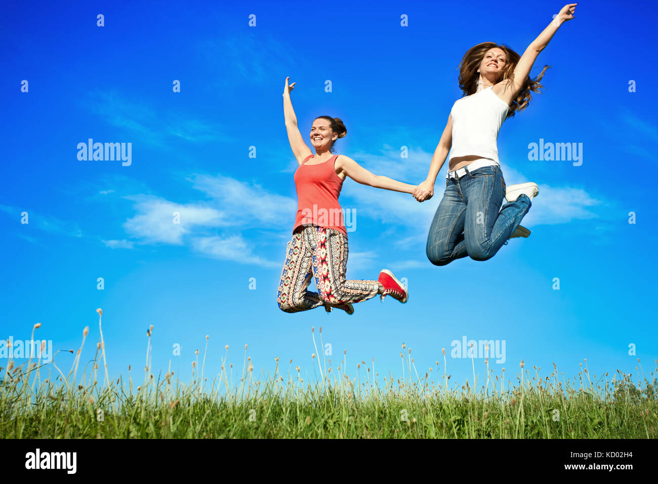 Two happiness young women jumping over blue sky Stock Photo - Alamy