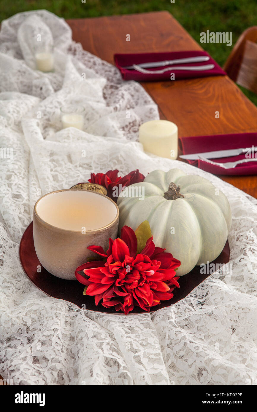 Seasonal table centerpiece setting of a pumpkin, candle and flower. Stock Photo