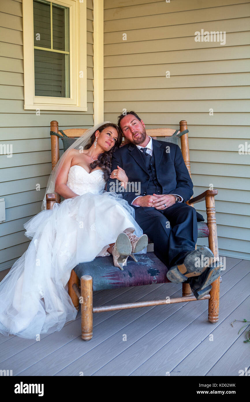 Newly married couple sit in a rocking chair wearing their tuxedo and ...