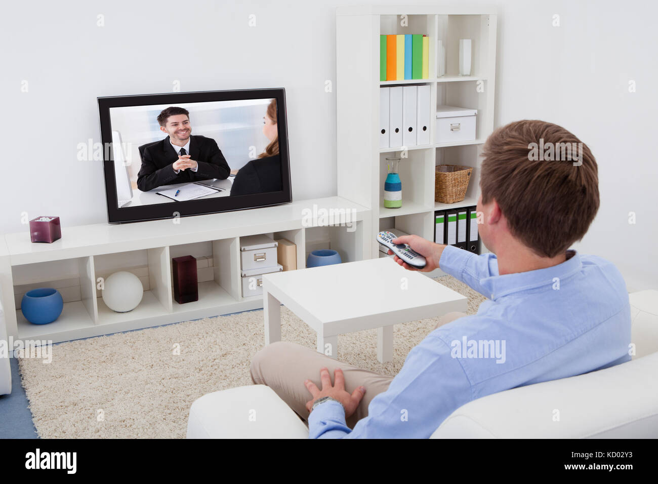 Rear View Of A Man Sitting On Couch Watching Television Stock Photo