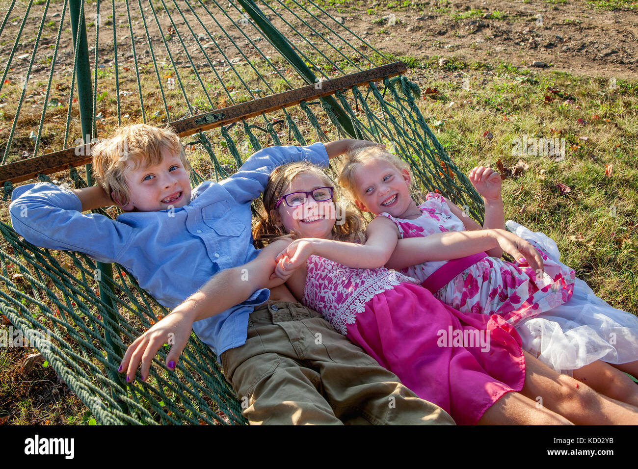 Three happy children swinging together on a hammock. Stock Photo