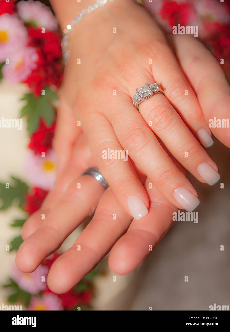 Closeup of newlywed couple's hands featuring wedding rings. Soft focus. Stock Photo