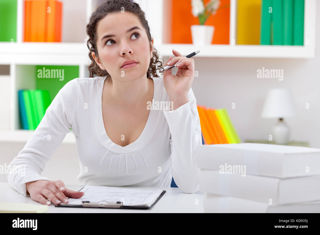 Thinking teenager girl sitting at desk and learning Stock Photo