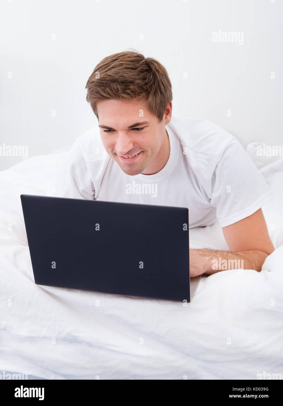 Portrait Of A Young Man Lying On Bed Using Laptop Stock Photo - Alamy
