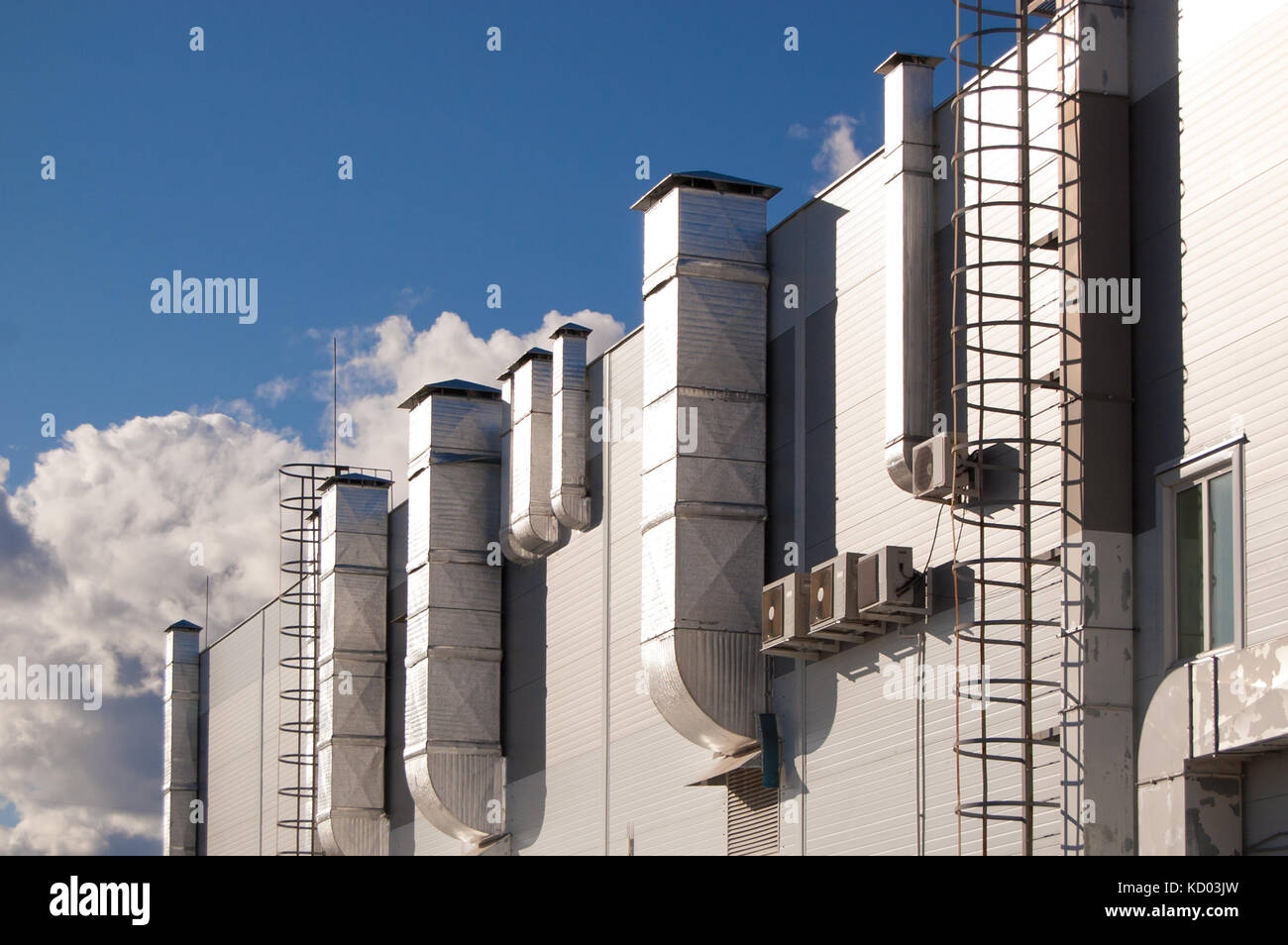 industrial building with ventilation pipes and air conditioners against the blue sky Stock Photo