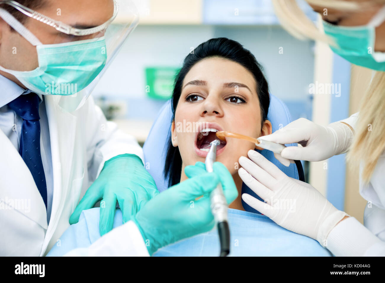Female patient with dentist and assistant, wearing masks and gloves