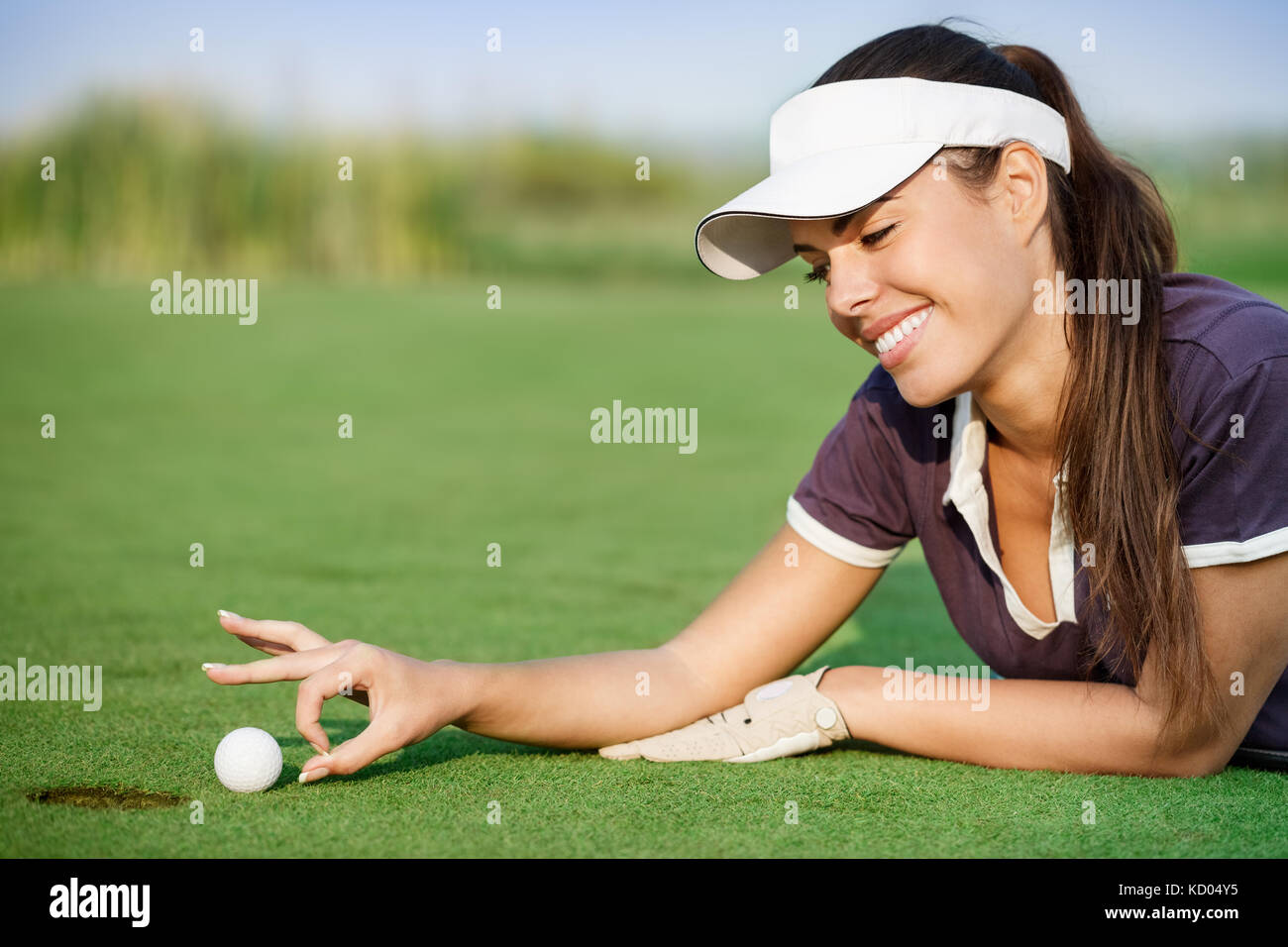 Woman pushing golf ball into the hole Stock Photo Alamy